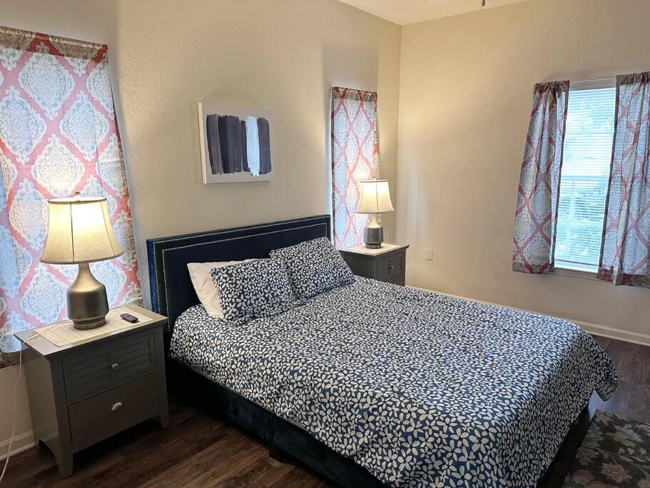 ein Schlafzimmer mit einem Bett, zwei Lampen und zwei Fenstern in der Unterkunft Private 1/1 Unit in Sanford, FL in Sanford