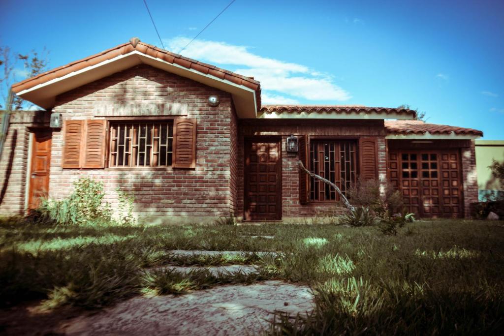 uma pequena casa de tijolos com duas janelas e um quintal em El patio de Malek em Cosquín