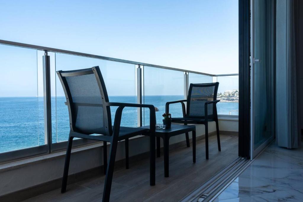 two chairs on a balcony with a view of the ocean at Seafront 2 Bedroom Apartment In Prime Area in St. Paul's Bay