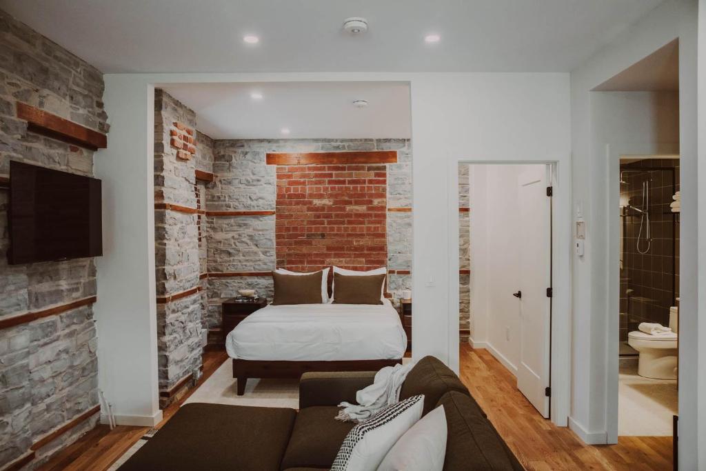 sypialnia z łóżkiem i ceglaną ścianą w obiekcie The Colby House - Downtown Kingston w mieście Kingston
