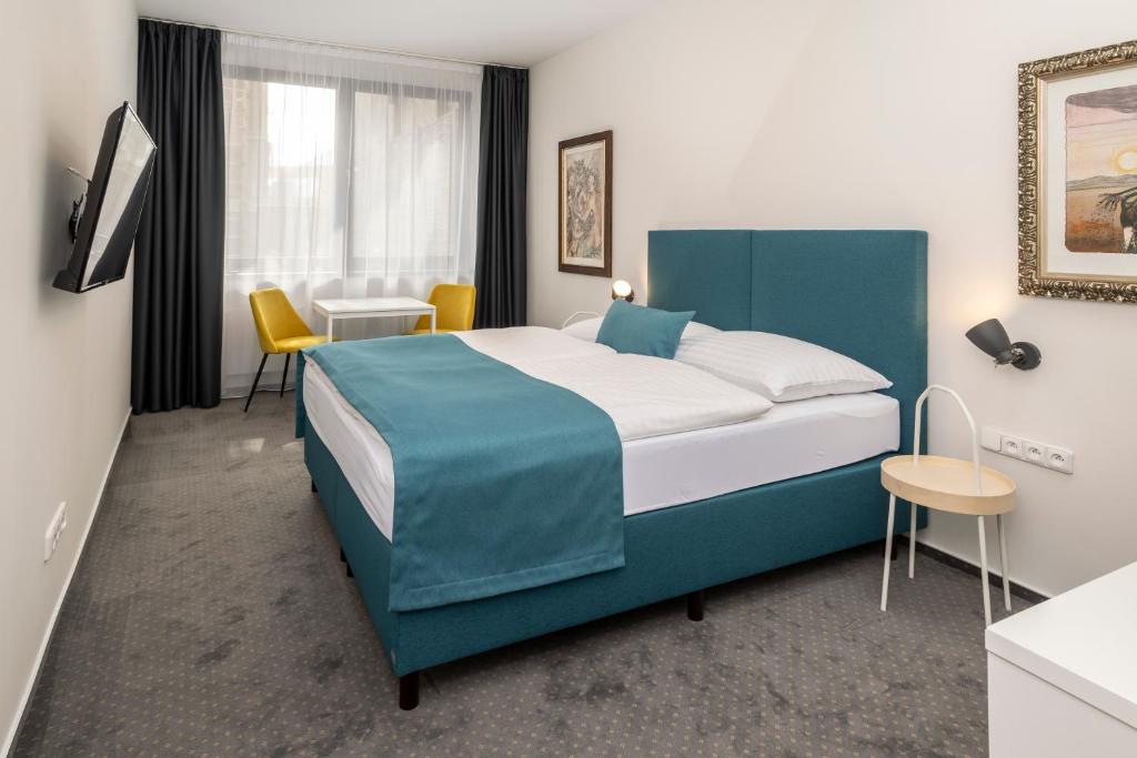 オストラヴァにあるHotel VP1のベッド、テーブル、椅子が備わるホテルルームです。