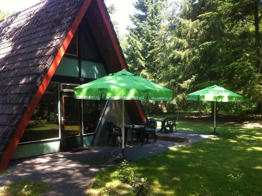 dos sombrillas verdes sentadas fuera de una cabina en Ferienhaus in Stramproy mit Möblierter Terrasse en Stramproy
