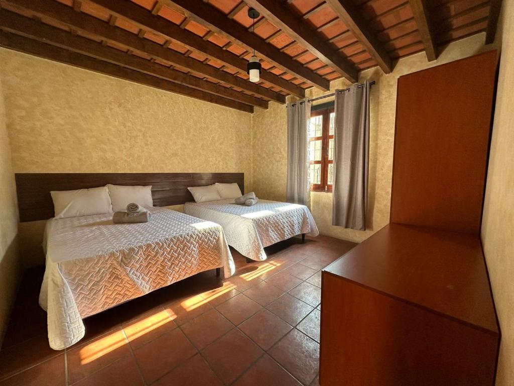 a bedroom with two beds and a dresser in it at Casa Los Héroes in Antigua Guatemala