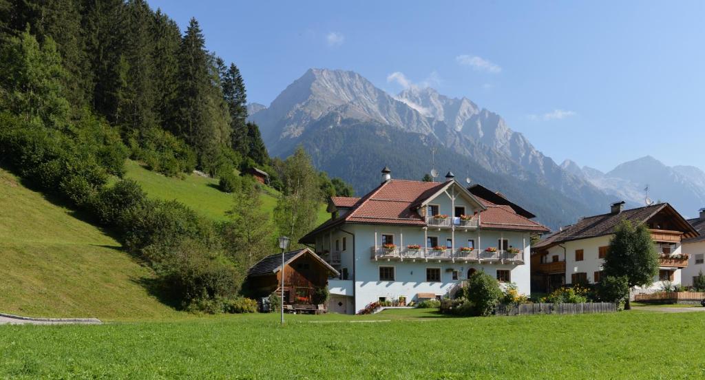 une grande maison sur une colline avec des montagnes en arrière-plan dans l'établissement Residence Edelweiss, à Anterselva di Mezzo