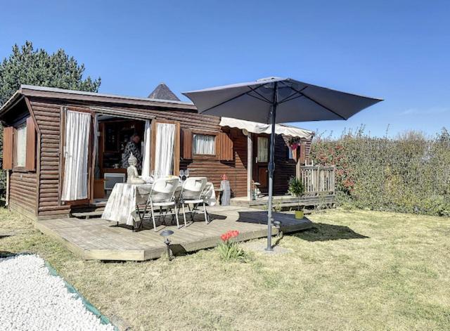 a wooden cabin with a table and an umbrella at Le chalet de Blonville in Blonville-sur-Mer