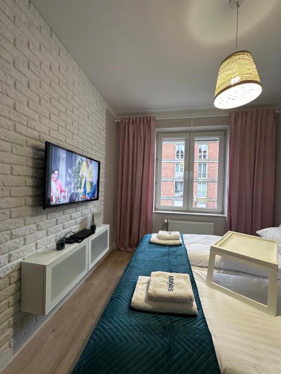 a bedroom with two beds and a tv on a brick wall at Maya's Flats & Resorts 59 - Most Miłości in Gdańsk