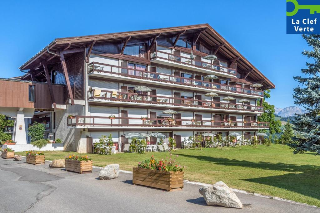 un grand bâtiment avec quelques plantes devant lui dans l'établissement Résidence Pierre & Vacances Le Mont d'Arbois, à Megève