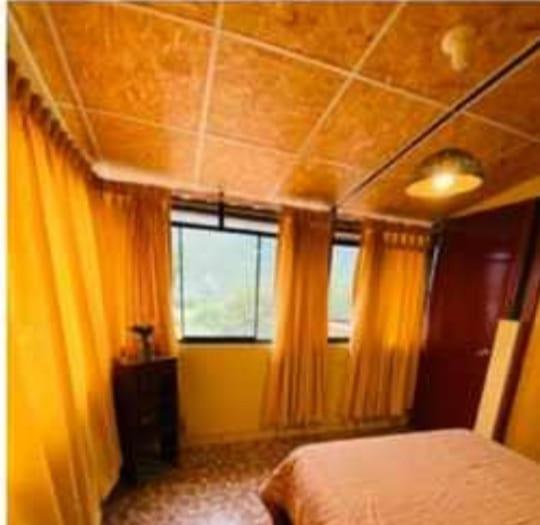 1 dormitorio con cortinas amarillas, 1 cama y ventana en Albreth - Hotel Bungalows, en Huaraz