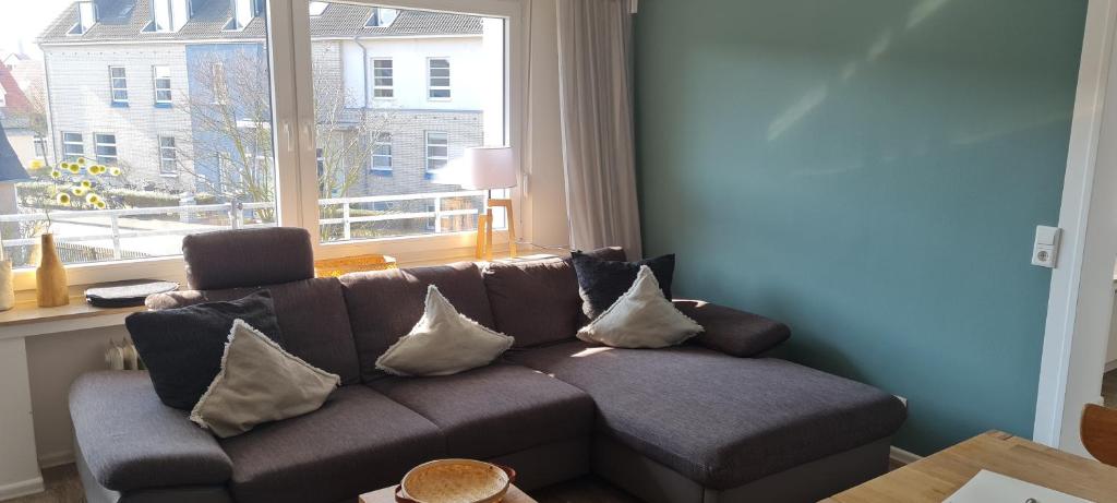 a couch with pillows in a living room with a window at Dünenrose Seegras Nr 41 in Norderney