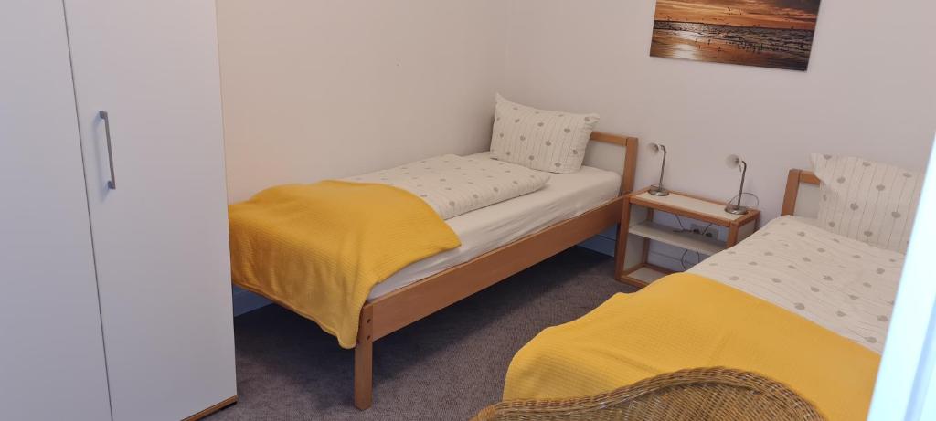 a room with two twin beds with yellow sheets at Ferienhaus Pauls Ferienhaus Pauls, Whg 02 in Norderney