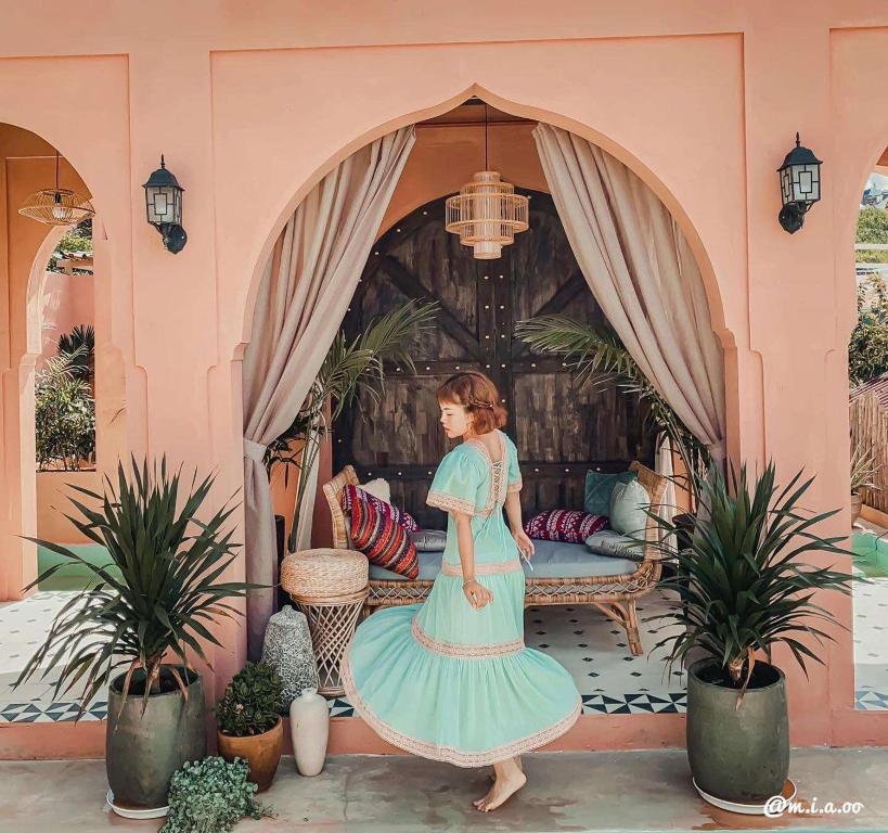 una donna in un vestito blu in piedi davanti a una stanza di Malá home coffee a Da Lat