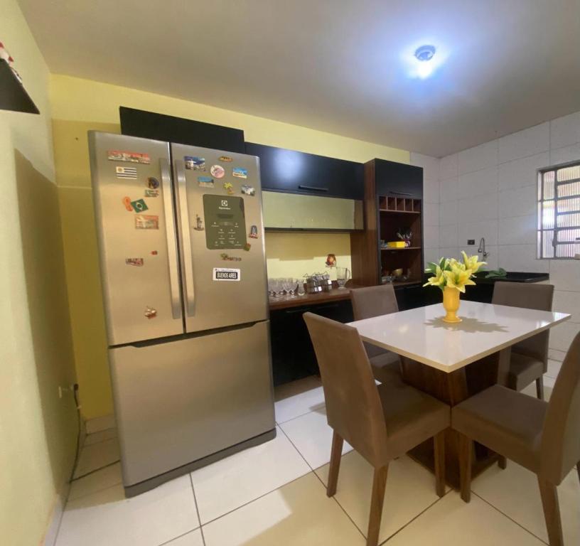 a kitchen with a table and a refrigerator at Casa Camargo - mobiliada, cozinha completa in Campo Grande