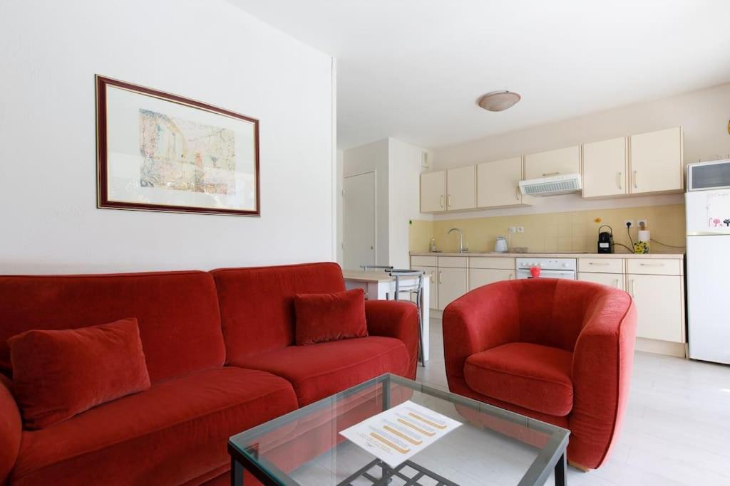 un salon avec un canapé rouge et deux chaises dans l'établissement Domaine des Palmiers - Piscine- Parking - Tennis - Clim, à Cannes