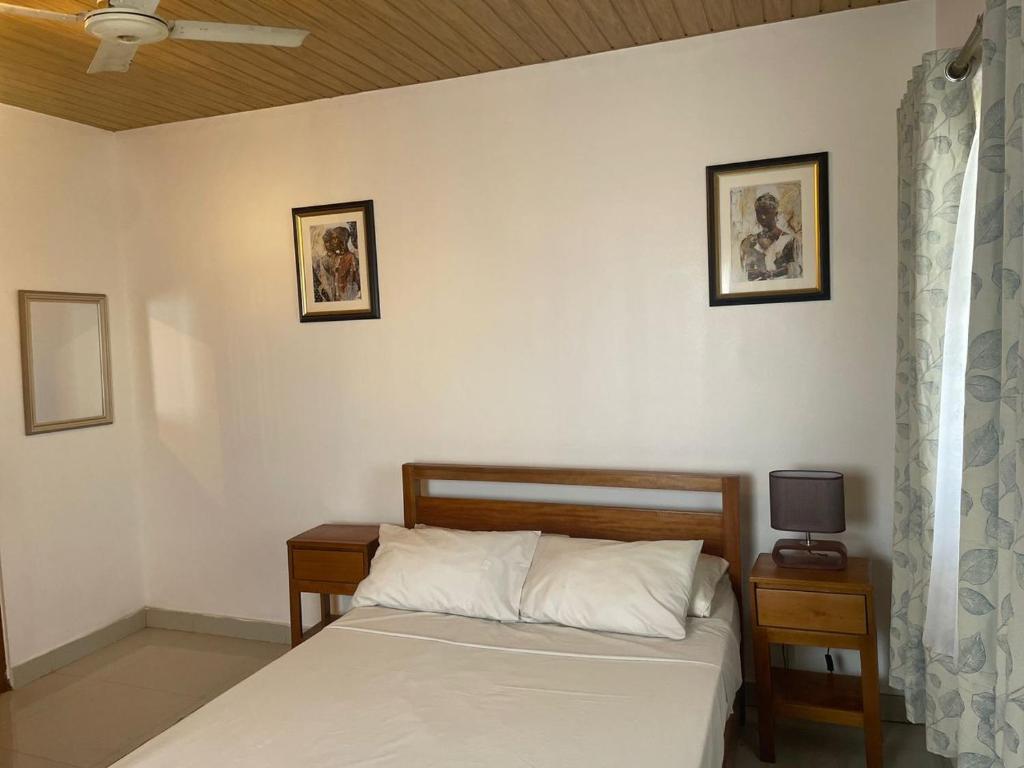 een slaapkamer met een bed en twee foto's aan de muur bij short/long stay in Okponglo
