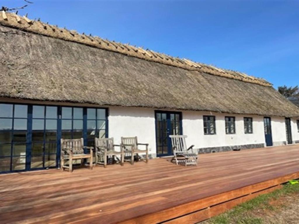 a building with a thatched roof and a wooden deck at Apartment Niesina - all inclusive - 35m from the sea by Interhome in Hundested