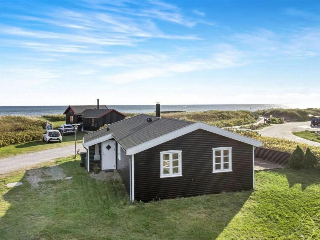 een klein huis op het gras bij de oceaan bij Holiday Home Baarde - all inclusive - 60m from the sea by Interhome in Grenå