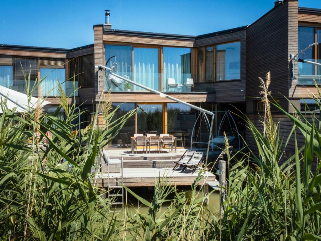 uma casa com um deque de madeira e janelas de vidro em Holiday Home Relax Lodge am See by Interhome em Neusiedl am See