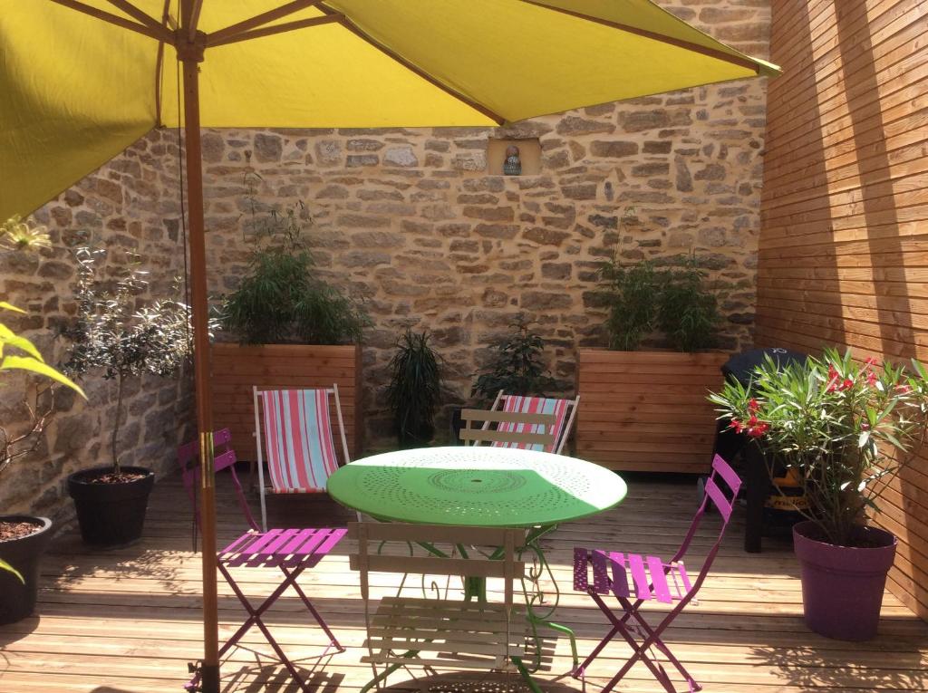 un patio avec une table, des chaises et un parasol dans l'établissement Maison avec patio centre ville quartier calme, à Arbois