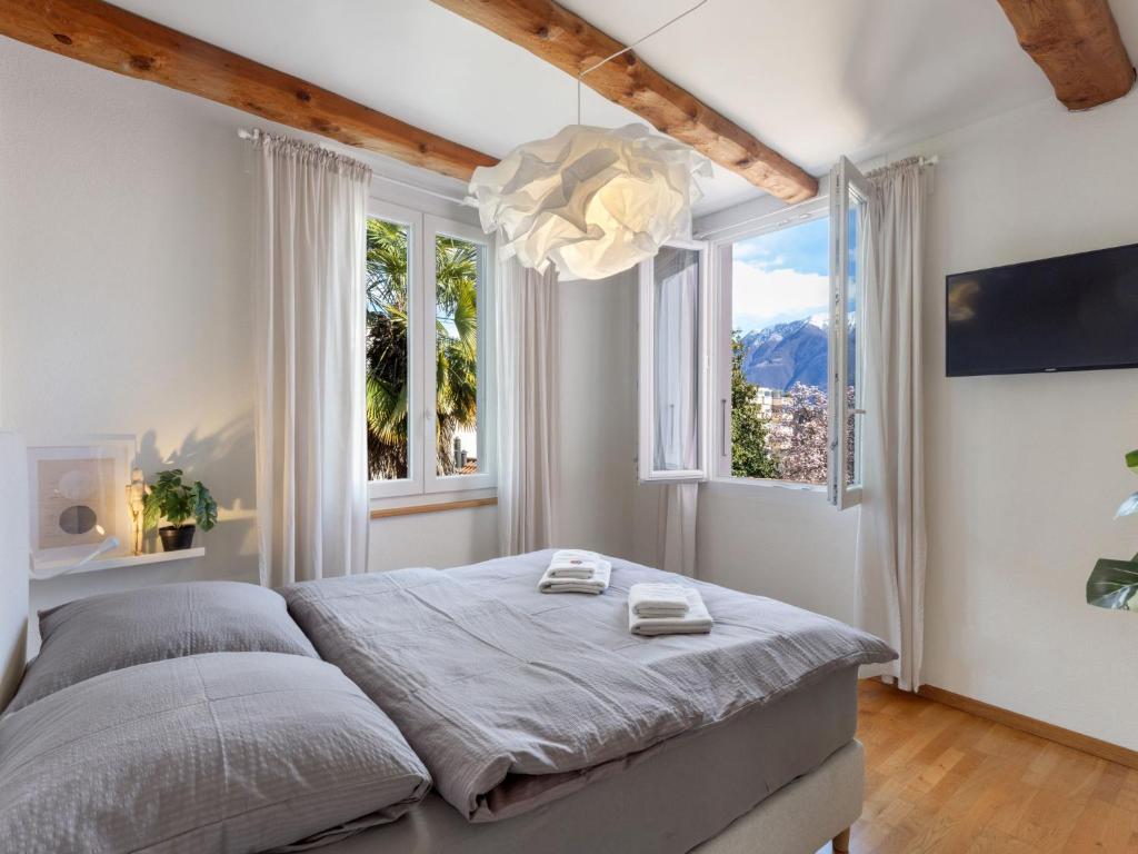 a bedroom with a bed and two windows at Studio Da Gina Honey Moon Ascona by Interhome in Ascona