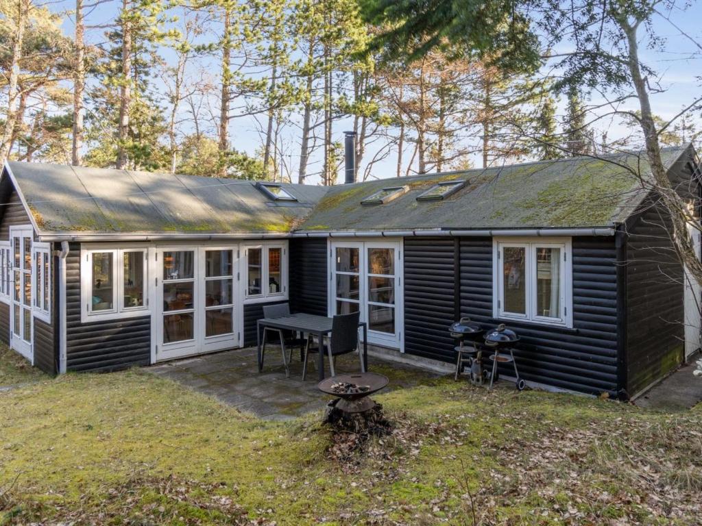 ein kleines schwarzes Haus mit einem Picknicktisch im Hof in der Unterkunft Holiday Home Borghild - all inclusive - 1km from the sea by Interhome in Nykøbing Sjælland