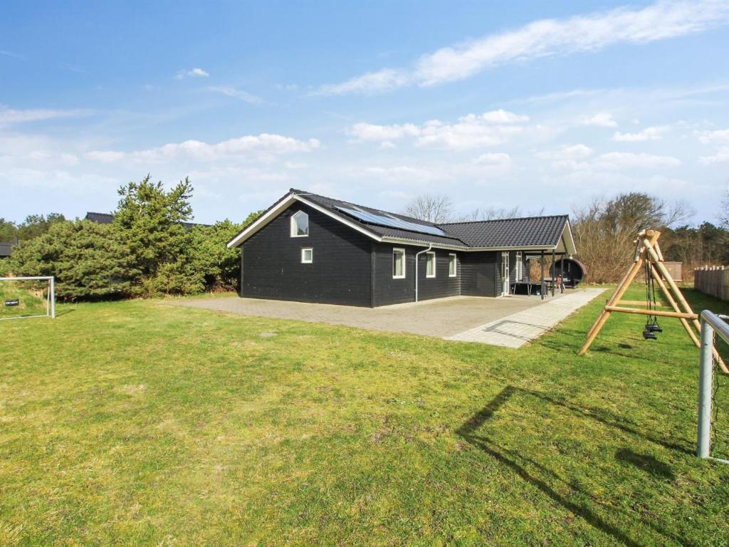 a black house with a telescope in a yard at Holiday Home Blaga - all inclusive - 3-3km from the sea by Interhome in Rømø Kirkeby