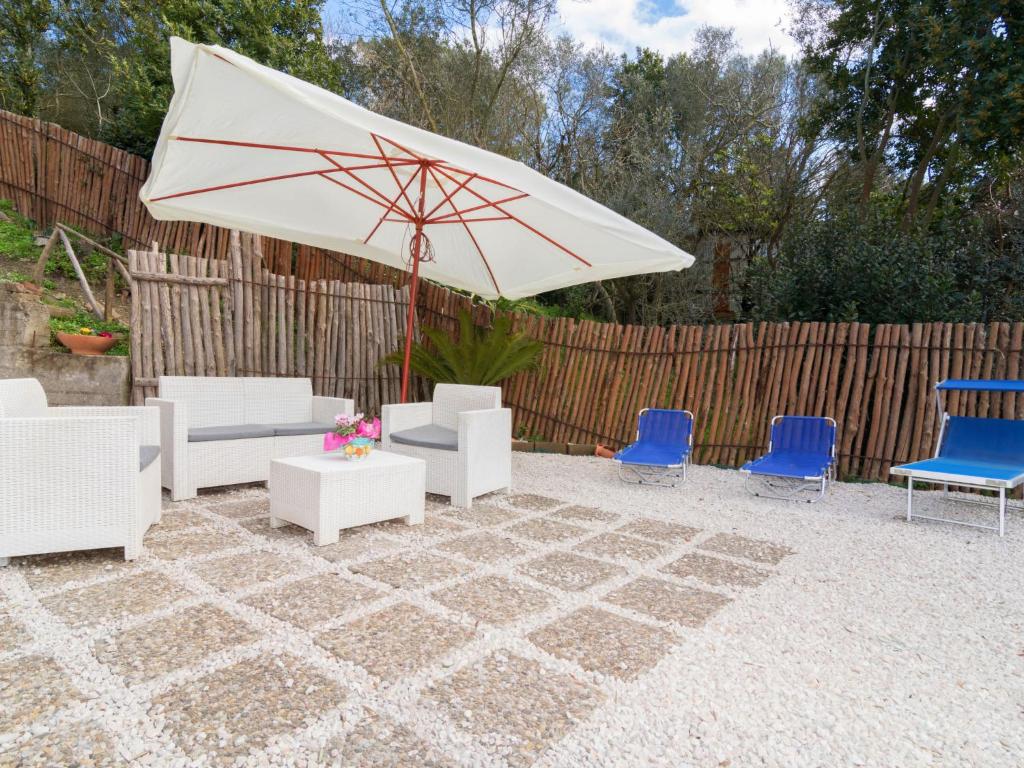 eine Terrasse mit einem weißen Sonnenschirm und blauen Stühlen in der Unterkunft Holiday Home Candy-3 by Interhome in Nerano