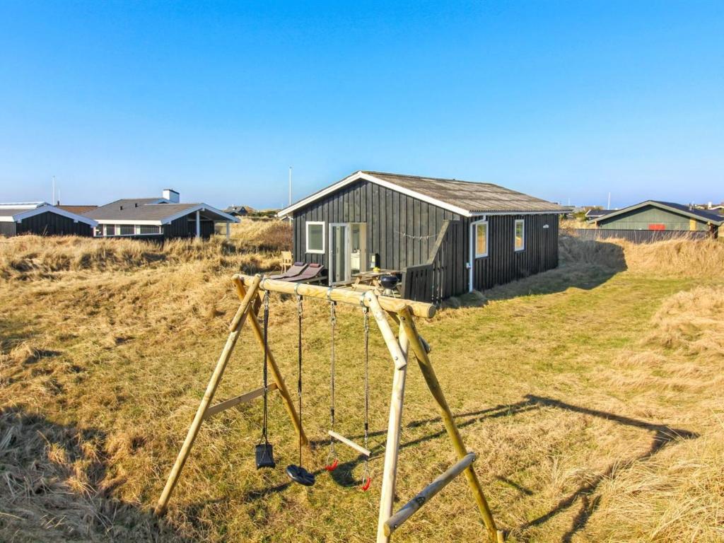 a swing set in a field in front of a house at Holiday Home Carstina - all inclusive - 400m from the sea by Interhome in Skagen