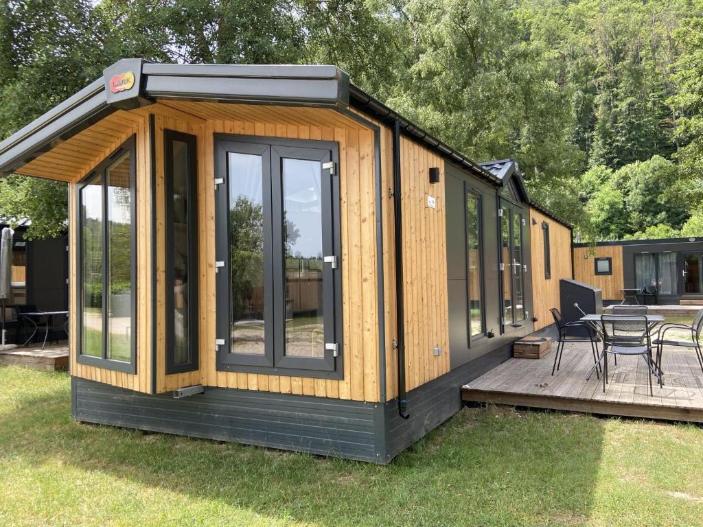 a large wooden cabin with a deck in the grass at Holiday Home Tiny Haus ChrisTine by Interhome in Riedenburg
