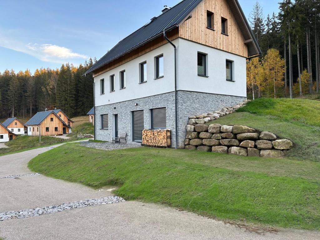 um grande edifício branco com uma parede de pedra ao lado de uma estrada em Apartment Chalupa 13ka - Dolní apartmán by Interhome em Smržovka