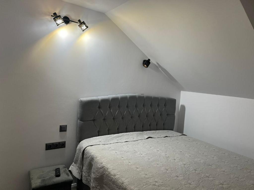 a bedroom with a bed with two lights on the wall at Apartament Mansarda Venus in Râmnicu Vâlcea