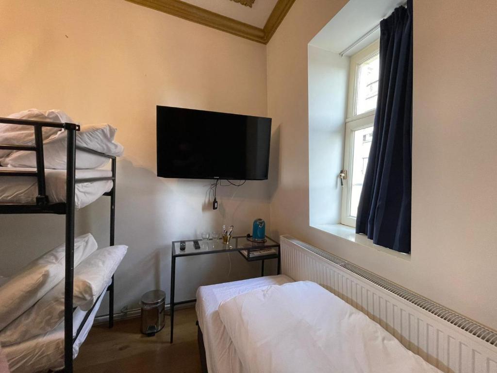 Zimmer mit 2 Etagenbetten und einem Flachbild-TV in der Unterkunft Amsterdam Rembrandt Square city center Hotel in Amsterdam