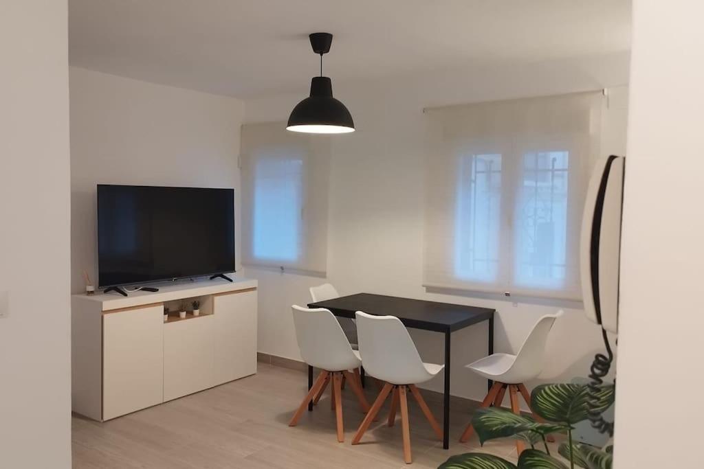 ein Wohnzimmer mit einem Tisch, Stühlen und einem TV in der Unterkunft Apartamento moderno a 1km de Granada in Granada