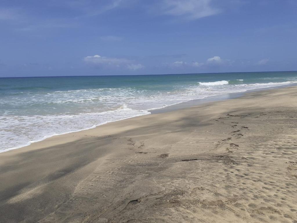 uma praia com pegadas na areia e no oceano em Apto Martins - Prédio Residencial Inês nº23 em Vila do Maio