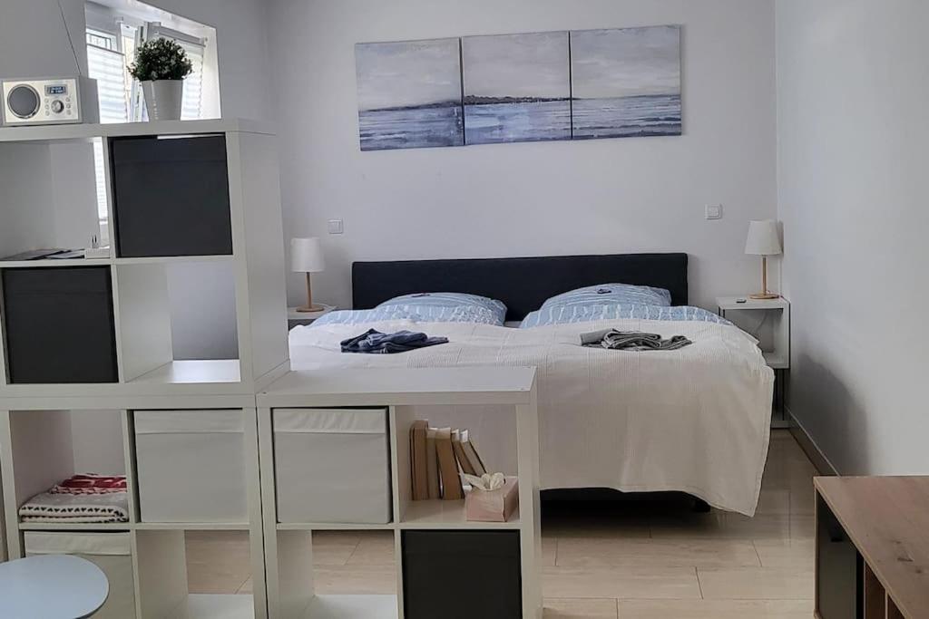 a white bedroom with a bed and a white shelf at Schönes, kleines 1 Zi Appartment in Bad Krozingen