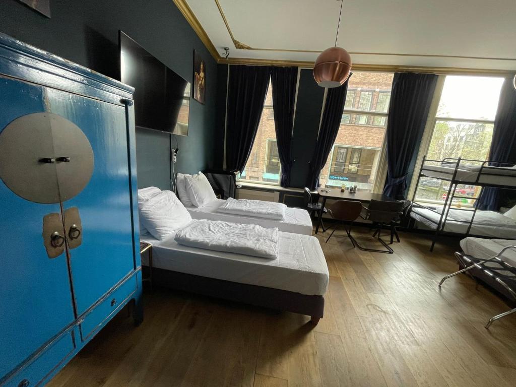ein Zimmer mit zwei Betten und einem Tisch darin in der Unterkunft Amsterdam Rembrandt Square city center Hotel in Amsterdam