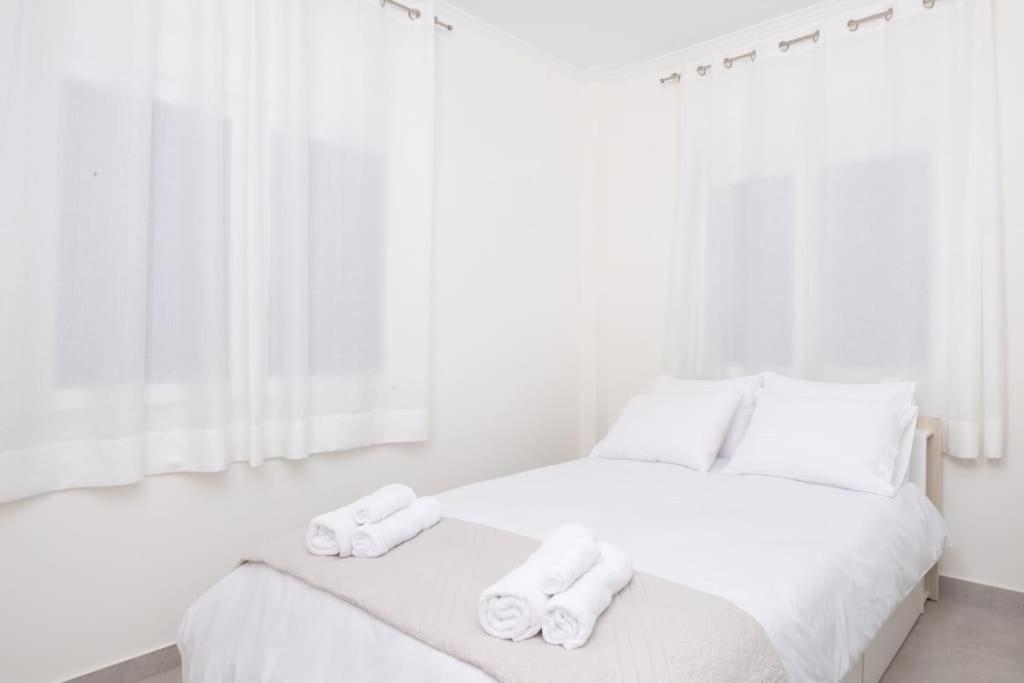 a white bedroom with a bed with towels on it at Zografou House Living in Athens