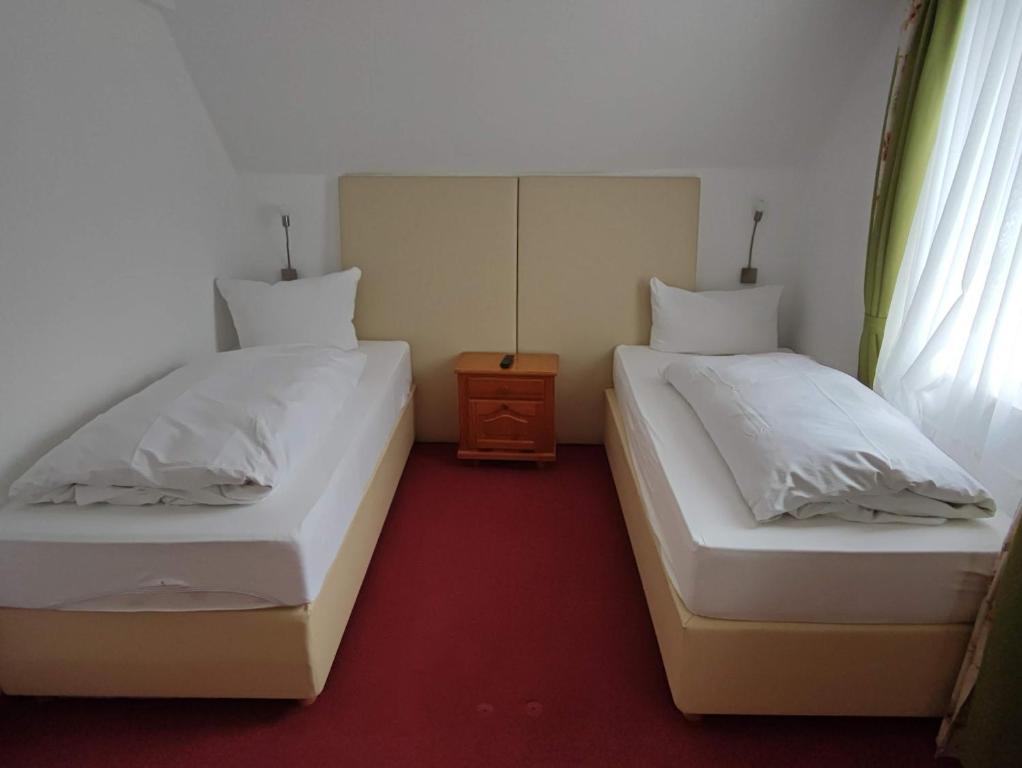 2 łóżka pojedyncze w pokoju z czerwonym dywanem w obiekcie Room in Guest room - Pension Forelle - double room w mieście Forbach