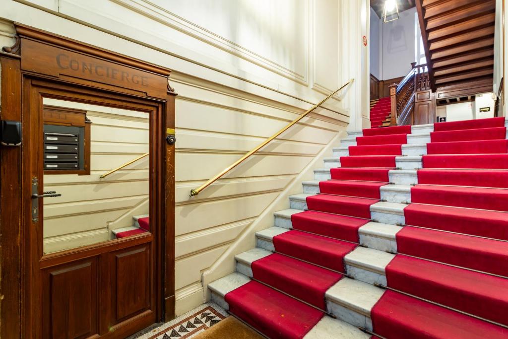 un escalier rouge et blanc à côté d'une porte dans l'établissement La petite conciеrgeriе du Grand-Rond, à Toulouse