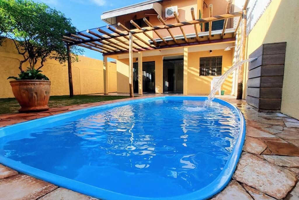 a blue swimming pool in front of a house at Sobrado Com Piscina proximo aeroporto in Campo Grande
