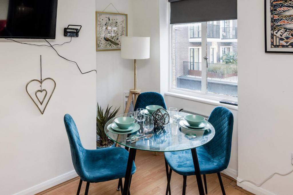 comedor con mesa de cristal y sillas azules en Affordable Flat in Fitzrovia en Londres