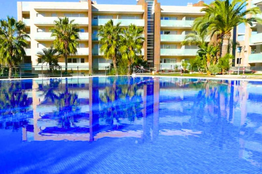 uma grande piscina com palmeiras e um edifício em Lido Planet Costa Dorada em Salou