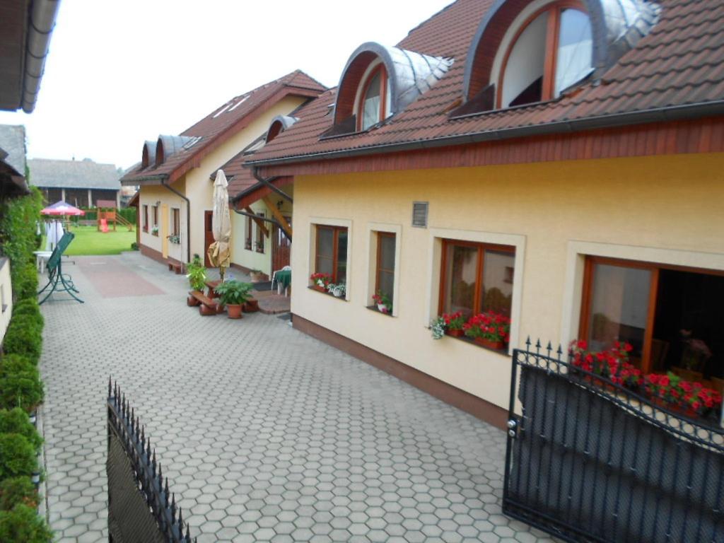a courtyard of a house with a fence and flowers at Penzion Rosnicka Liesek in Trstená