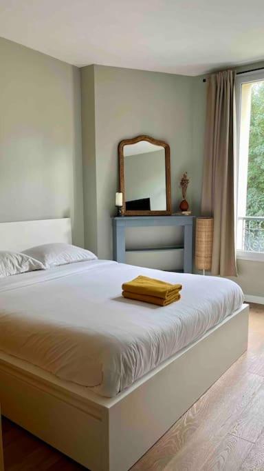 - une chambre avec un lit et un miroir dans l'établissement Appartement cozy pour découvrir Paris., à Issy-les-Moulineaux