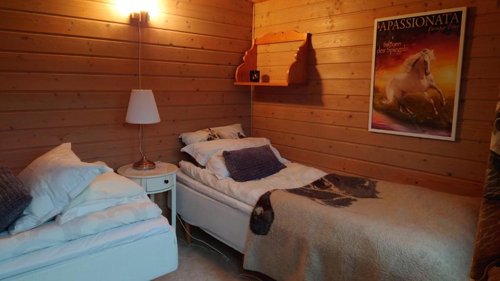 a bedroom with two beds and a poster of a horse at Lilla Röaby in Bräkne-Hoby