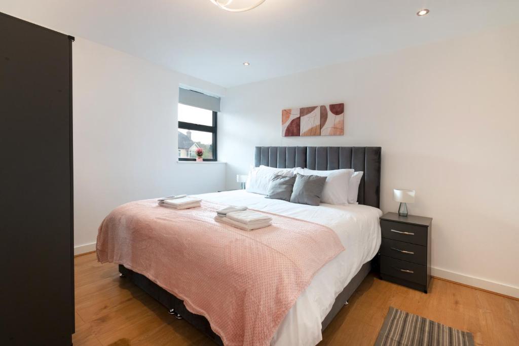 a bedroom with a large bed with a pink blanket at Modern Serviced One Bedroom Flat - Sleeps 4 - Near High Street & Train Station - CR5 London in Coulsdon