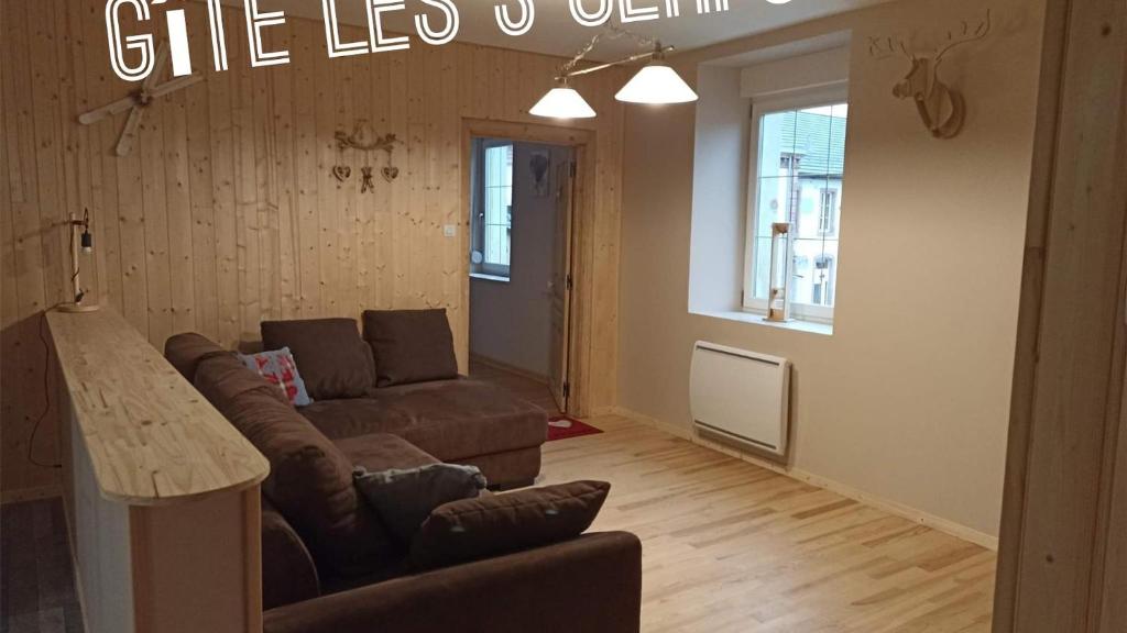 ein Wohnzimmer mit einem Sofa und einem Tisch in der Unterkunft Gîte Les 3 Cerfs - 3 étoiles in Plainfaing
