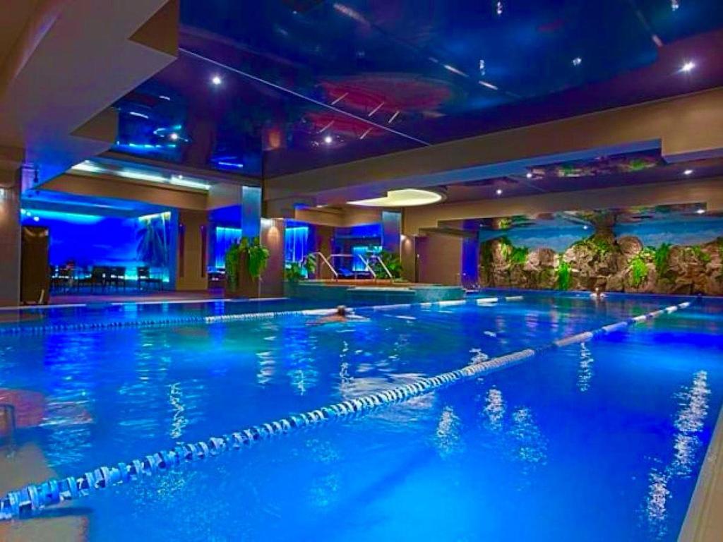duży basen w hotelu z niebieskimi światłami w obiekcie YamaLuxe Apartments - Silent & Warm With Many Facilities w Bukareszcie