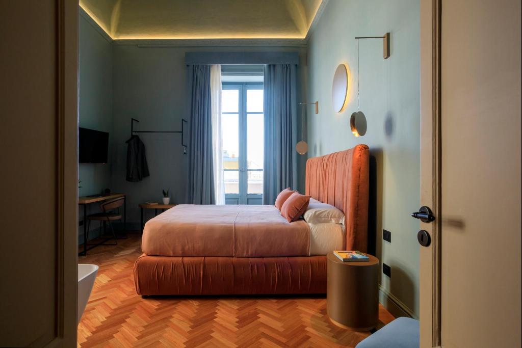 Schlafzimmer mit einem Bett, einem Schreibtisch und einem Fenster in der Unterkunft Maison Belmonte - Suites in Palermo in Palermo