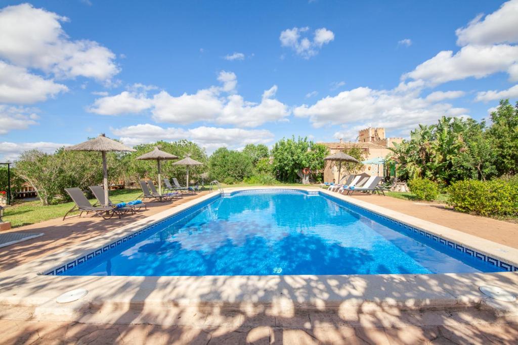 a swimming pool with chairs and umbrellas in a yard at Finca Son Marimon in Santanyi