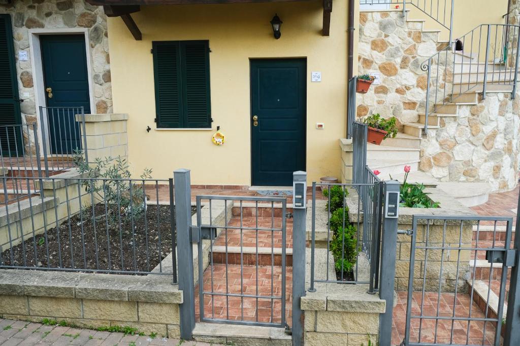 ein Haus mit zwei blauen Türen und einem Zaun in der Unterkunft Madonnina Tuscany House in Montefollonico